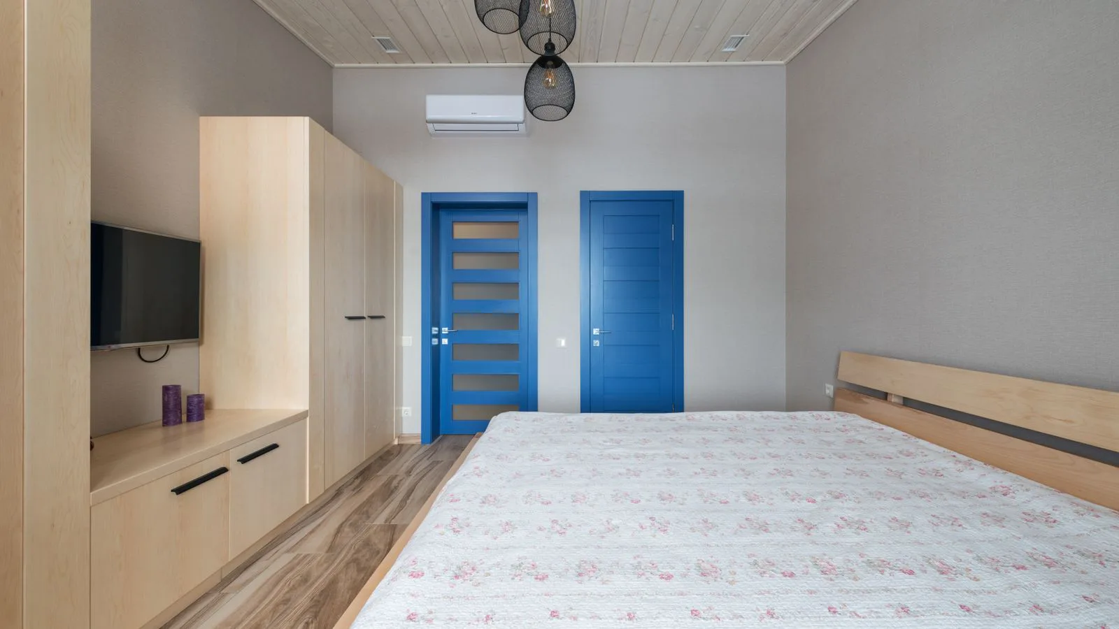 A bedroom with a wall-mounted air-conditioning unit above the door.