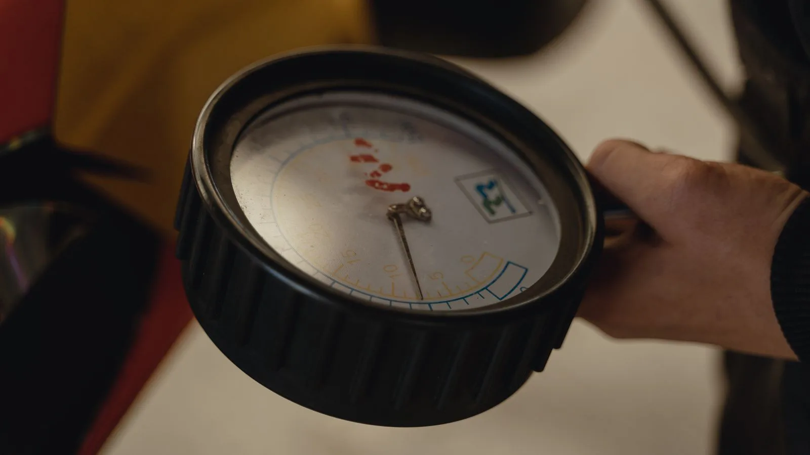 A hand holding a dial tyre-pressure gauge.