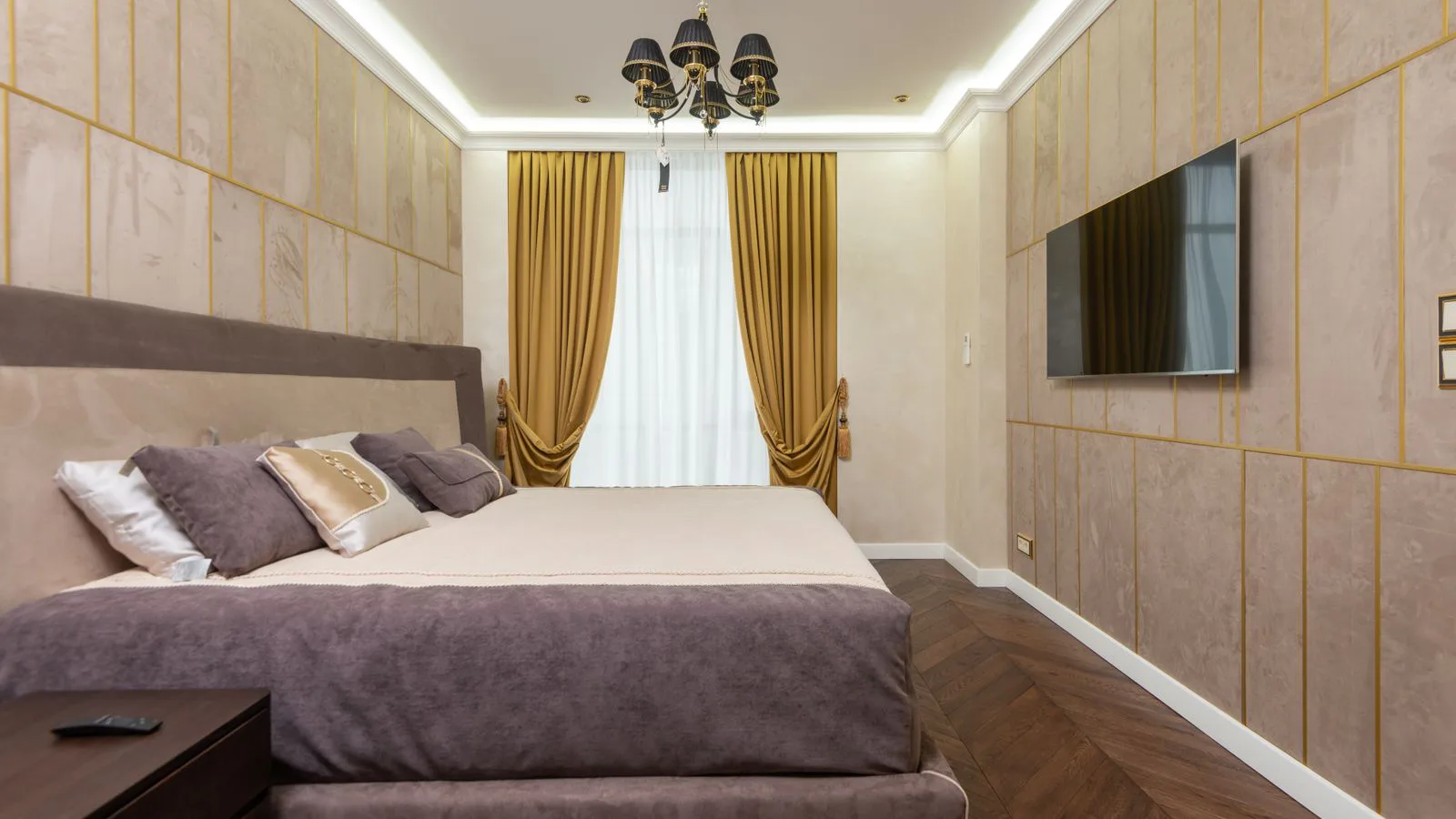 A bedroom with a large television mounted on the wall.