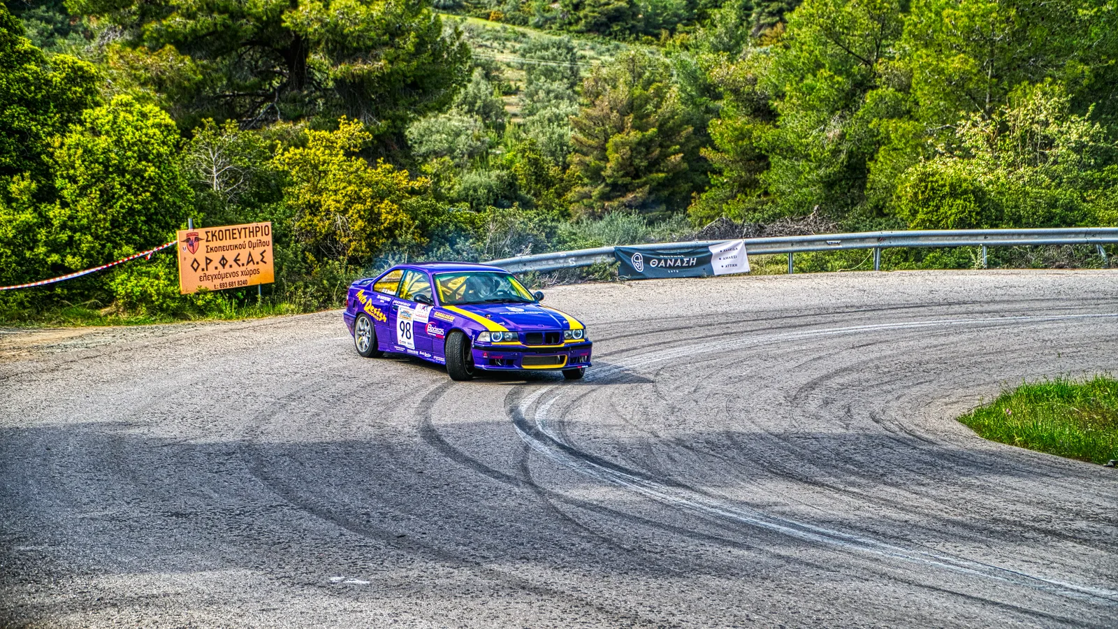 A car leaning through a bend on a winding road.