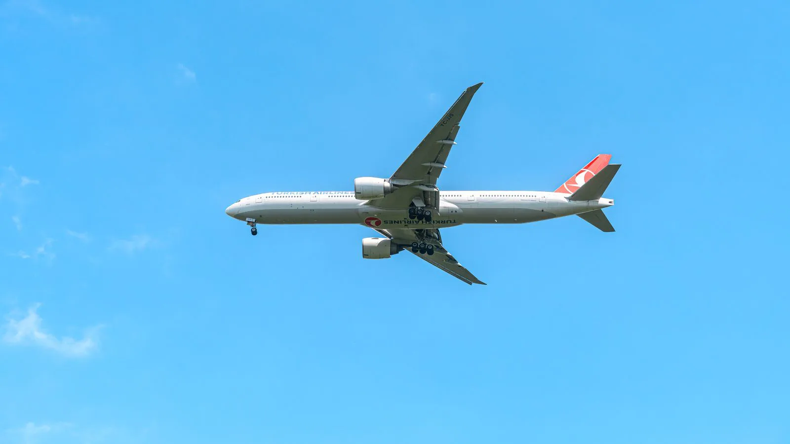 A commercial airliner in flight against a clear blue sky.